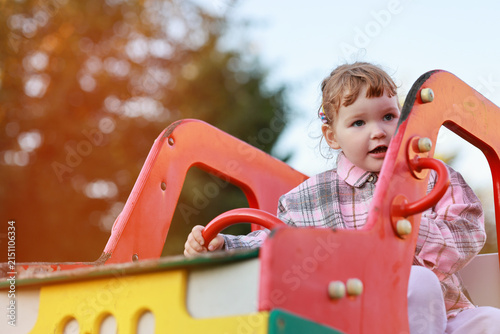 Foto Little girl playing in a toy car on a green lawn
