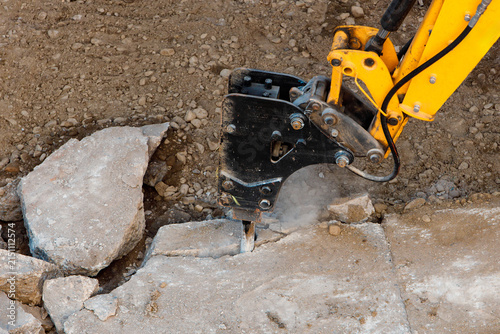 Workers use a machine to break concrete on a construction site