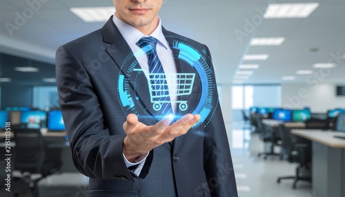 Businessman holding digital shopping cart hologram in office