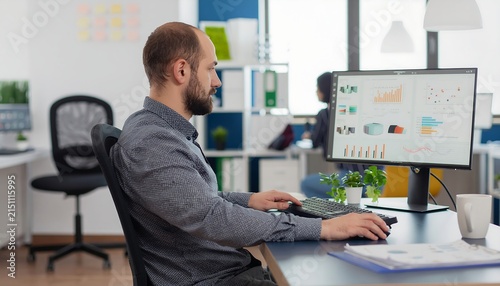 Businessman working on computer in modern office with charts on screen