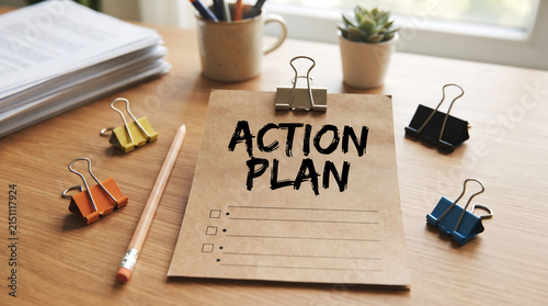Notebook on desk with action plan checklist and office supplies for productivity.