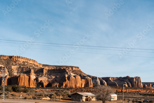 Rustic Route 66 landscape in Arizona, USA with striking red rock, a small wooden building, power lines, and rugged desert scenery beneath a clear blue sky
