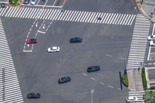 Foto Aerial view of a large signalised intersection serving a dense business district, a motorcyclist crossing ahead of the traffic stream, showing the rhythm of a working district
