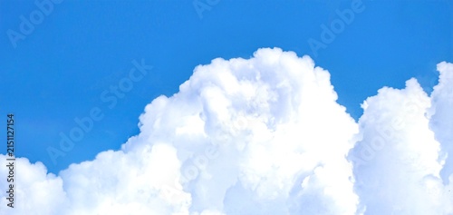 Принти на полотні Massive fluffy white cumulus clouds building up against vibrant blue sky backgro