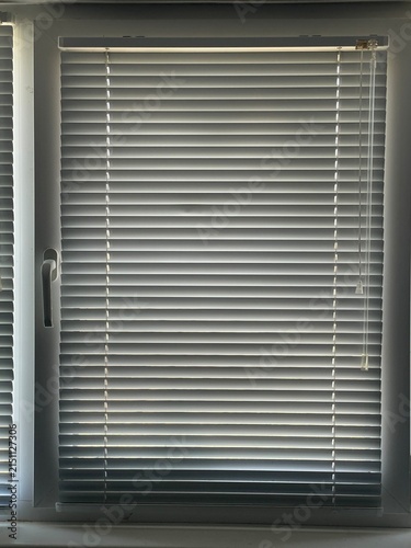 Modern White Plastic Window Blinds Closed Tight to Block Bright Sunlight in a Room