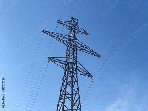High Voltage Electric Power Transmission Tower Against a Clear Blue Sky with Soft Clouds