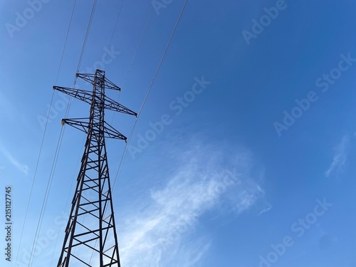 High Voltage Electric Power Transmission Tower Against a Clear Blue Sky Background