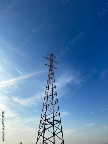 High Voltage Electric Power Transmission Tower Against a Clear Blue Sky Background