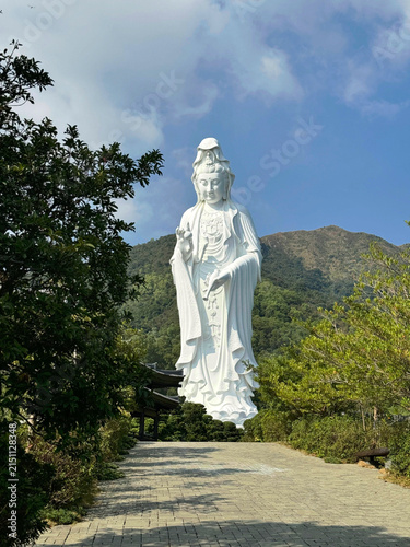 Bild auf Leinwand White Guanyin Bodhisattva Statue Against Mountain and Forest Landscape
