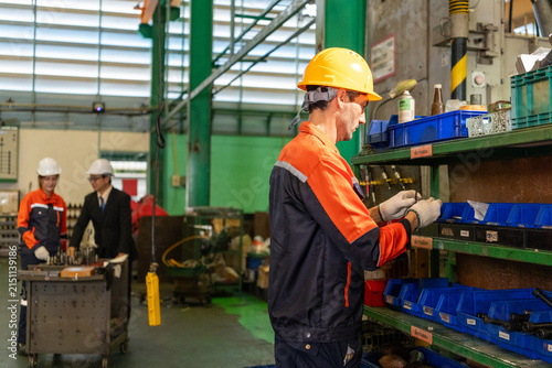 Engineer factory worker hard hat industrial shelf tool safety uniform inside workshop sorting equipment with team
