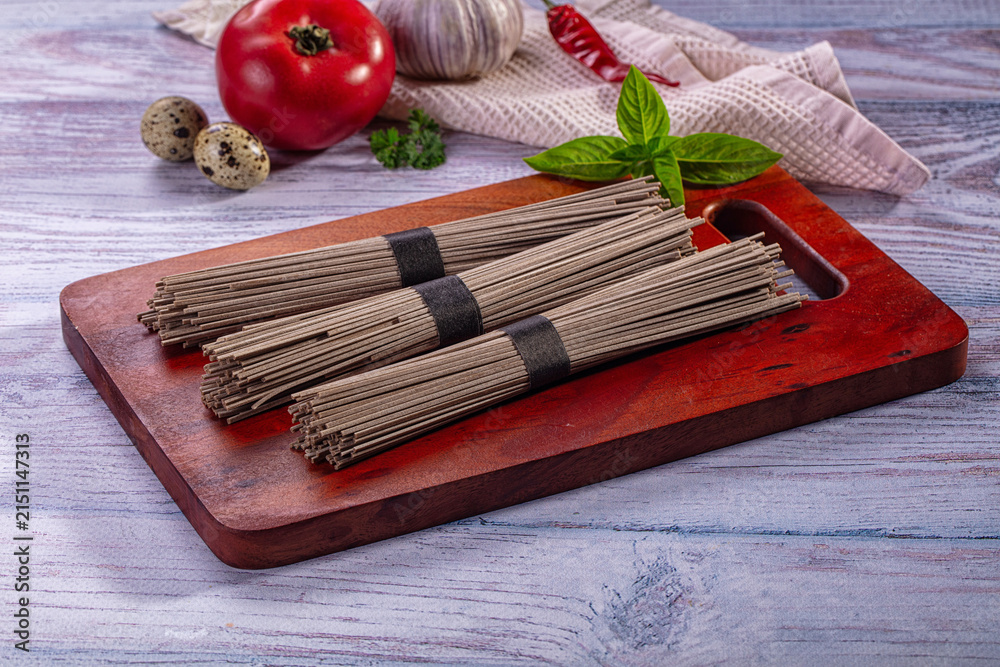 Fototapeta premium Soba noodles on wooden board with fresh ingredients