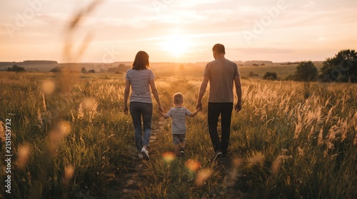 Family strolling through tall meadow grass during golden hour