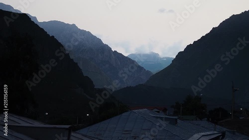 Dramatic landscape of rugged rocky mountain peaks shrouded in thick white fog and dense clouds. Majestic alpine scenery at high altitude with misty summits under an overcast sky — ideal for travel, ad