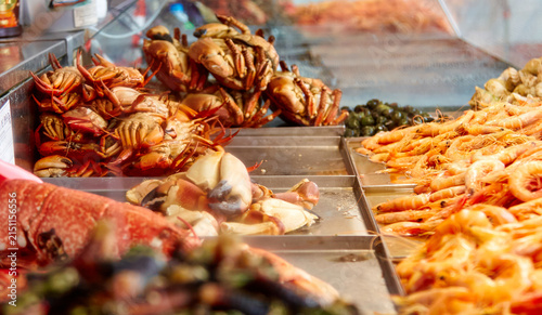 Obraz na płótnie Fresh seafood display at a fish market stall featuring crabs, shrimp, and variou