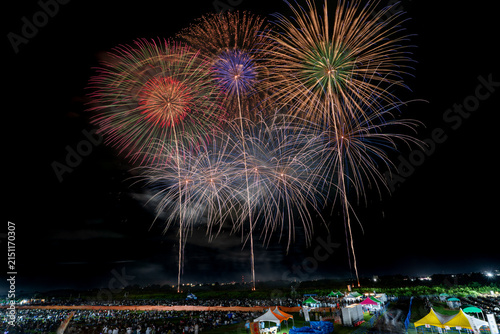 Green, blue and gold fireworks overlapping at festival climax in Japan