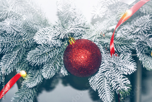 Card. Merry Christmas and Happy New Year. Christmas tree decorated with a red glass ball on a branch. Snow. Holiday. Noel.