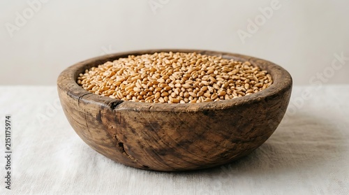 A rustic wooden bowl filled with raw organic wheat grains.