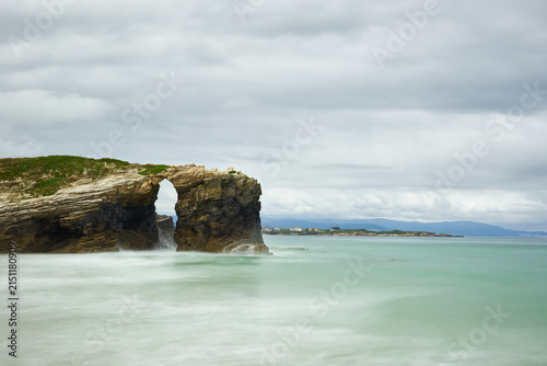 Moody long exposure of misty sea and rock at Praia das Catedrais, Beach of the Cathedrals in Ribadeo, Galicia Spain