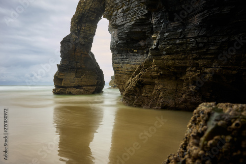 Moody long exposure of misty sea and rock at Praia das Catedrais, Beach of the Cathedrals in Ribadeo, Galicia Spain