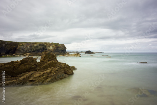 Moody long exposure of misty sea and rock at Praia das Catedrais, Beach of the Cathedrals in Ribadeo, Galicia Spain