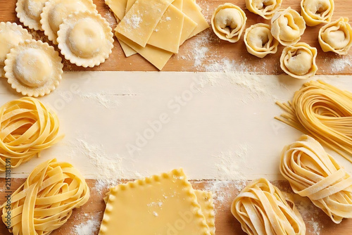 Flat lay of freshly made authentic Italian pasta variety with copy space on wooden background