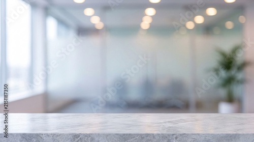 Blurred modern office interior with glass partitions and soft ceiling lights, copy space on marble table