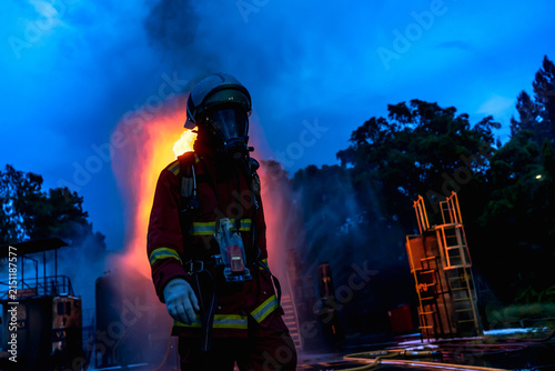 Dramatic silhouette of firefighter standing amidst intense flames and smoke during a structure fire