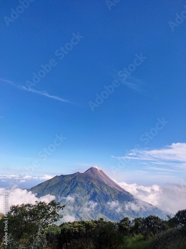 Fotografie Majestic view of Mount Merapi volcano rising above sea of clouds against clear blue sky in Indonesia, great shoot, best time