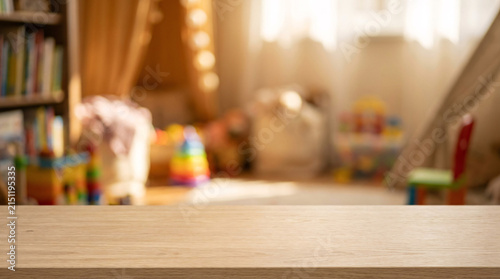 Warm, sunlit children's playroom with toys and a cozy reading nook, a wooden table in the foreground perfect for product placement