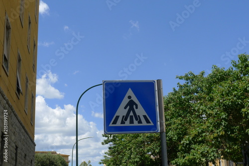 Blue Pedestrian Crossing Traffic Sign Against European Buildings and Blue Sky