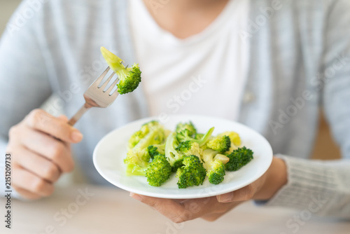 Diet in bored concept, Ketogenic, Low carb, Intermittent Fasting young woman dieting holding fork at broccoli on salad plate tired with eat fresh vegetables. Nutrition clean, healthy food good taste.