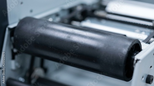 Barcode printer platen roller catching a soft reflection under overhead lab lighting - Medical Lab Barcode Label Printing Stock Photo
