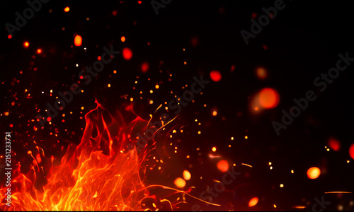Fiery flames and glowing embers with sparks against a dark black background