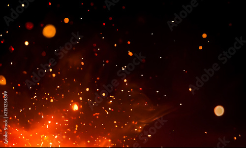 Warm fire sparks and glowing embers against a dark black background