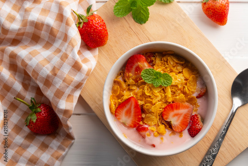 Cornflakes with fresh strawberries and yoghurt in white bowl.delicious healthy breakfast.Top view.