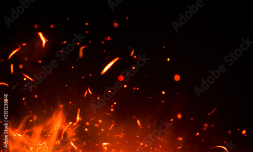 Fiery sparks and glowing embers rising from a dark flame with blurred motion