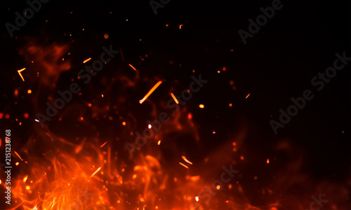 Fiery sparks and glowing embers rising from a vibrant orange and red flame background
