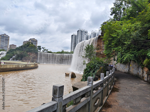 Stone pathway along the cascading artificial waterfall at Kunming Waterfall Park in Yunnan Province. KUNMING, YUNNAN, CHINA - JULY 31, 2026.