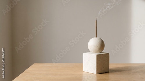 Minimalist incense holder with smoke rising against a light wall backdrop