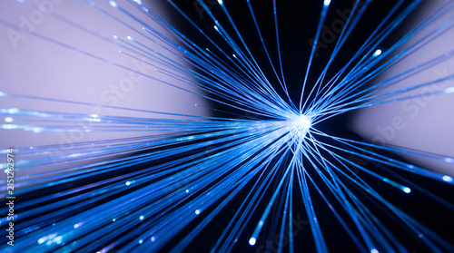 Close up view of fiber optic cables emitting bright blue light radiating outward from central point creating dynamic abstract pattern of digital communication technology