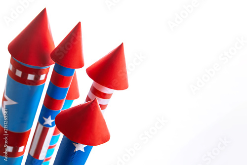 Fourth of July USA Independence Day festive celebration concept with copy space. Handmade craft paper rockets decorated with stars and stripes, isolated on white background.