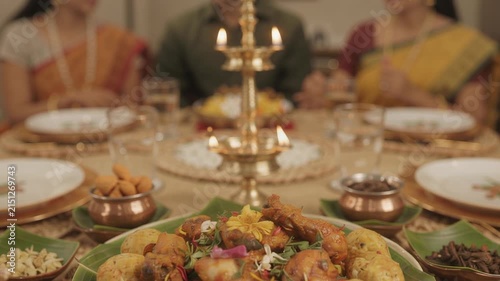 Indian festive dinner table with lit brass oil lamp and food