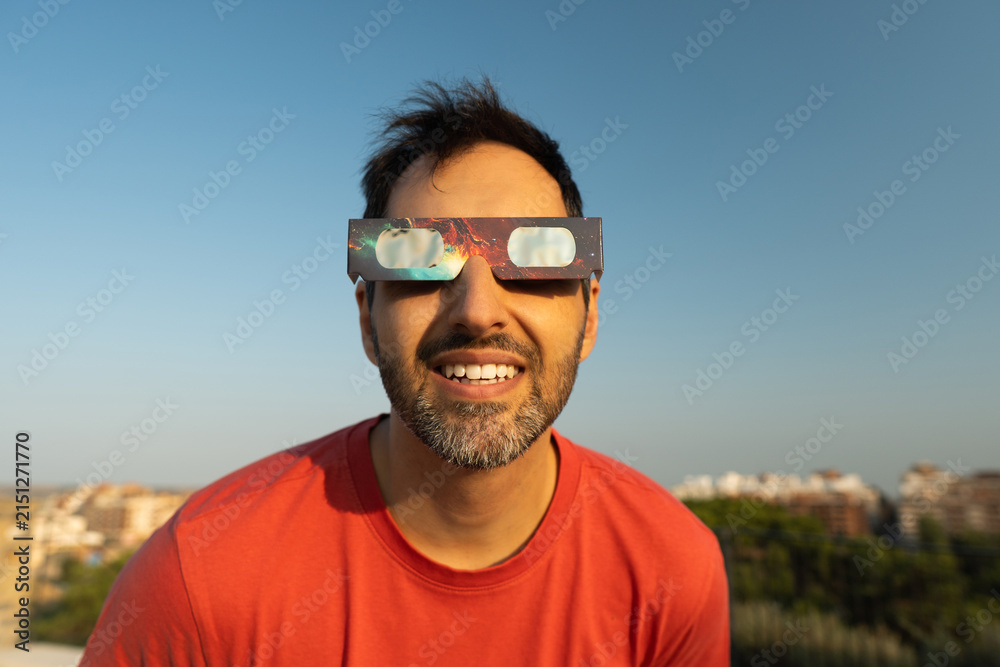 Obraz premium Man wearing protective solar eclipse glasses smiling outdoors