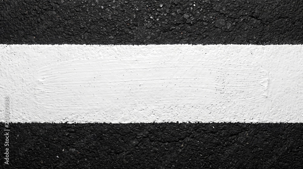 Fototapeta premium Bold white painted line on rough black asphalt texture, creating a striking contrast and clear road marking stripe