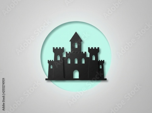 Black silhouette of a medieval castle fortress on a circular light blue