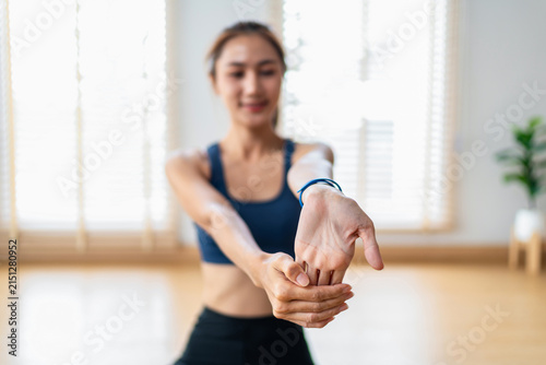 Woman stretches wrist during fitness workout at home improving flexibility and muscle health wellness body movement indoors