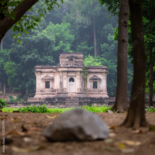 Ancient stone temple nestled in lush green forest.