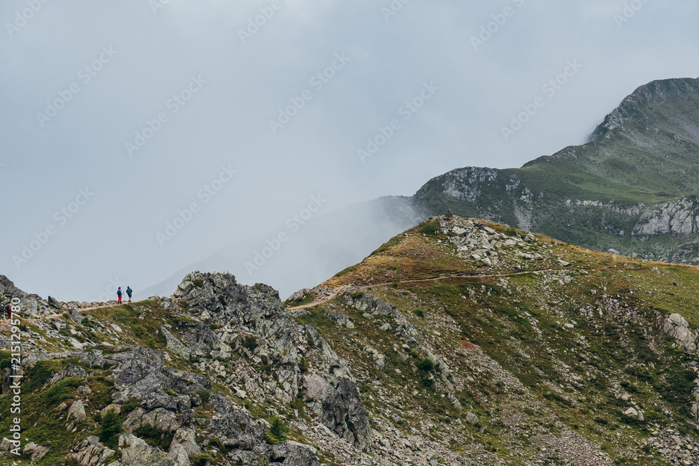 Obraz premium Trekkers Walking On Mountain Trail Towards Brevent Ridge In Misty Alpine Landscape French Alps Chamonix Valley High Altitude Hiking Route Scenic Vista Outdoor Adventure Extreme Trekking Experience
