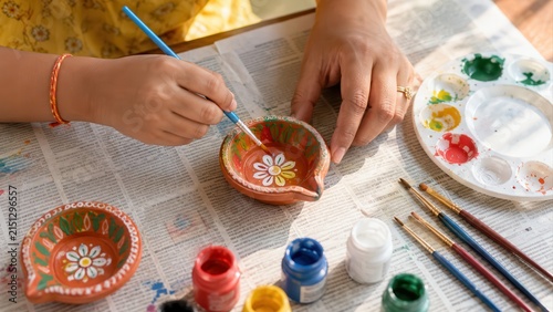 Child painting a colorful clay diya with adult guidance for Diwali festivities at home