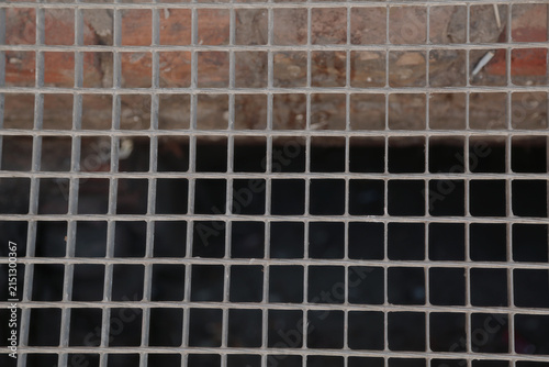 Metal Safety Grate with Square Grid Pattern Over Dark Opening